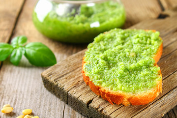 Homemade pesto sauce, bread. Ingredients. Cheese, garlic, basil, pine nuts, olive oil on an old wooden table.