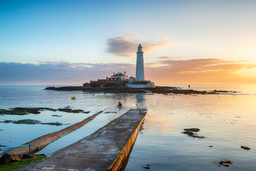 Kayakers paddle round the lighthouse at sunrise on St Mary's Island at Whitley Bay in Tyne and Wear...