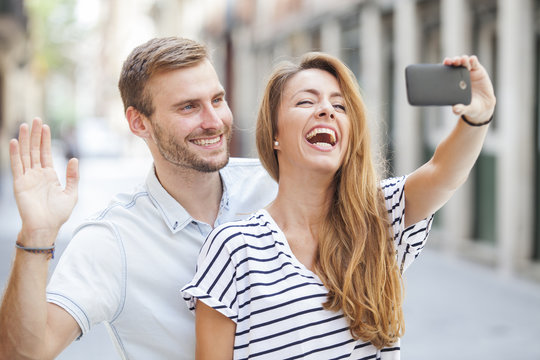 Smiling couple doing selfie on urban 
 background. Travel concept