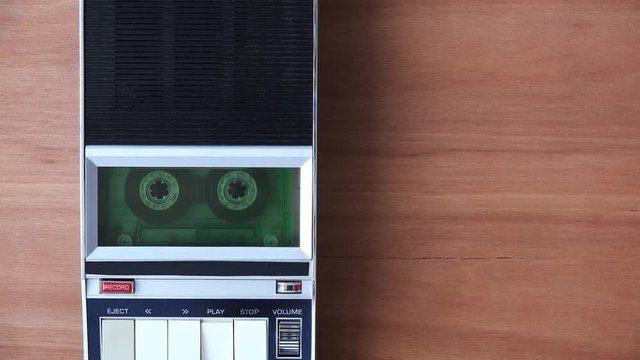 Audio cassette tape rolling in vintage player on the desk. Police interrogation sound recording retro technology concept for 1970s, 80s and 90s.
