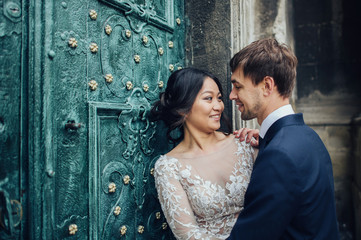 Elegant bride with groom walking near old catholic cathedral 