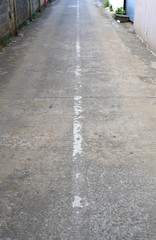Fototapeta premium Old grey block wall and cement road in alley, Thailand.