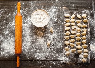 Pelmeni, dumplings with meat on dark wood background. Fresh dough.