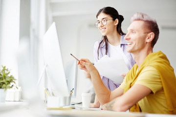 Successful designers discussing project on computer at office