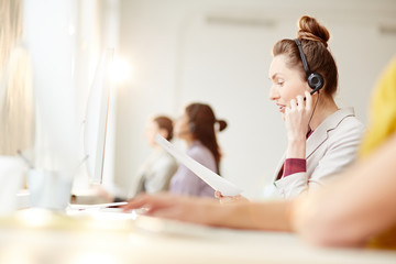 Businesswoman in headset communicating with client in call centre