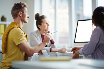 Fototapeta na wymiar Businessman showing computer screen to coworkers in creative office