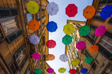 Fototapeta na wymiar Multicolored umbrellas in the sky above the streets in the center of Genoa, Italy.
