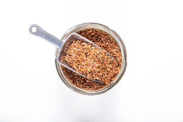 Healthy food concept Organic flax seeds with iron scoop in glass jar on white background