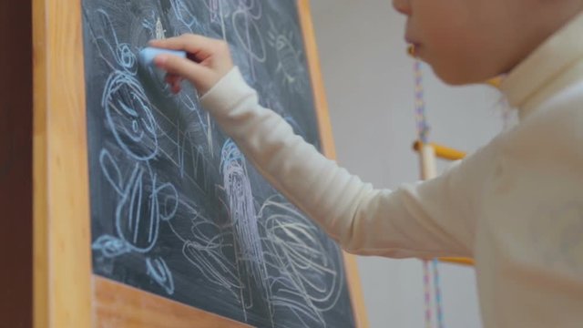 Little girl drawing with chalk on board