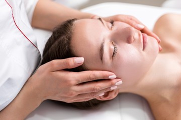 Obraz na płótnie Canvas Masseur doing massage on face of beautiful girl in spa salon