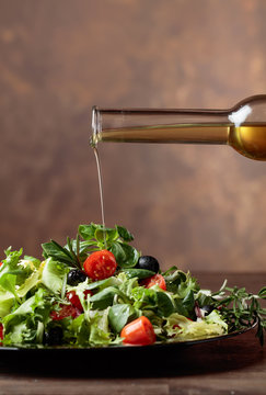 Green salad with olive oil pouring from a small bottle.