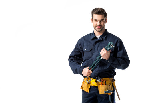 Smiling repairman wearing uniform with tool belt and holding wrench isolated on white