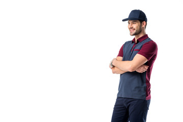 side view of smiling delivery man in cap with arms crossed isolated on white