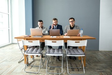 Three adult businesspeople sitting at desk in office