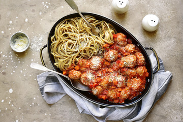 Meat balls in tomato sauce garnished with whole grain pasta in a skillet pan.Top view with copy space.