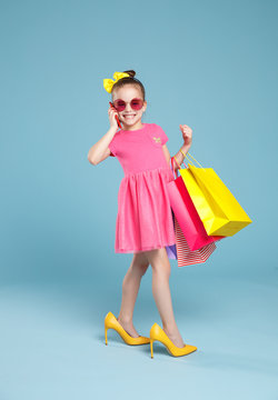 funny child girl fashionista in big mother's   shoes on colored background