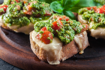 Bruschetta with fresh pesto, mozzarella and cherry tomatoes on cutting board