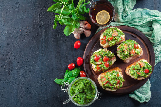 Bruschetta with fresh pesto, mozzarella and cherry tomatoes on cutting board