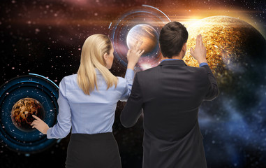business, future technology and people concept - businessman and businesswoman with planet and hologram over space background