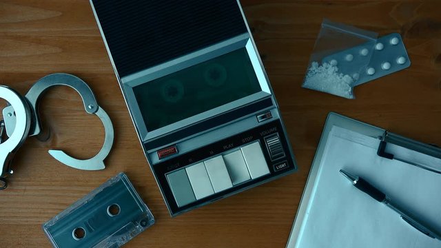Drug related police arrest concept, top view with tape player playing cassette with suspect's statement during police interrogation.