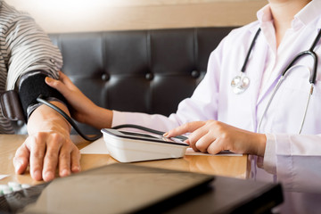 healthcare, hospital and medicine concept - doctor and patient measuring blood pressure by machine