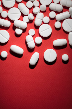 White pills and medicines on red background