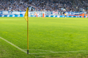 Obraz premium Corner flag at the football pitch, in the background players in action and audience.