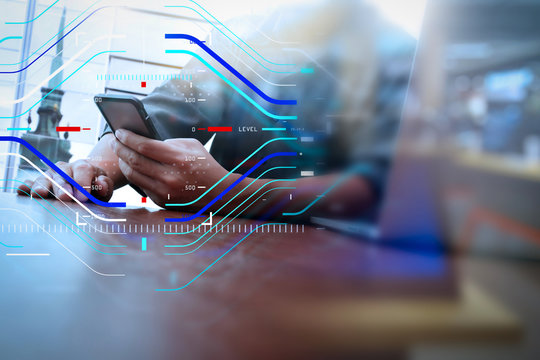 designer hand working and smart phone and laptop on wooden desk in office with london city background