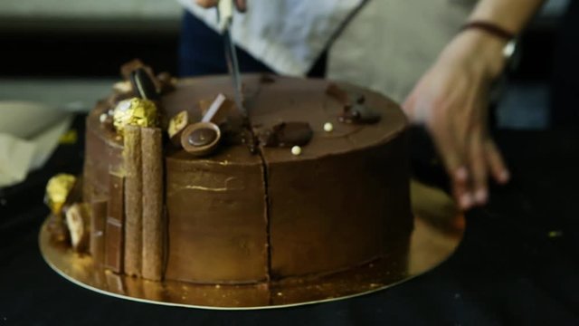 confectioner hands cut by knife big chocolate cake