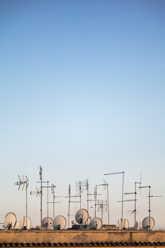 Satellite dishes and antennas on rooftop in evening light