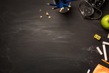 school supplies, alarm, pencils, apple on black chalkboard top view, copy space. concept: back to school, school's out, school holidays