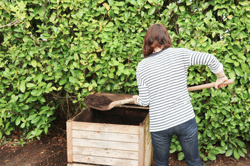 Working farmer woman caucasian female tumbling the compost with a pitch fork