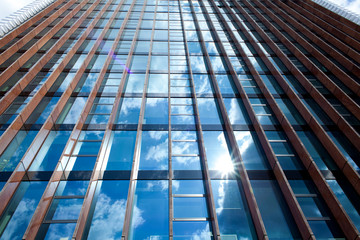 A large glass building with a reflection of the blue sky. Abstract blue background. Office building on a sunny day