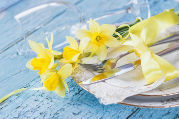 Set of tableware and a bouquet of yellow narcissus