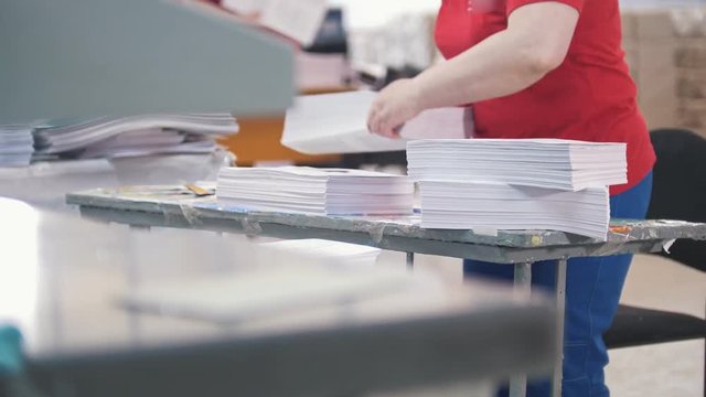 Female worker disassembles a stack of paper in the typography