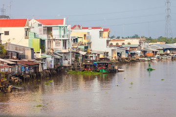 Fototapeta na wymiar Houses by the river at Cai Be Floating Market of Mekong Delta. Cai Be Market is one of most famous floating market in Vietnam