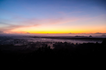 Sunrise silhouette forest with colorful sky and fog