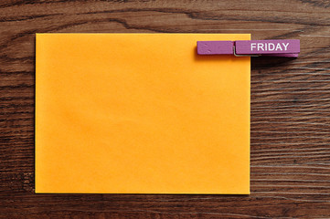 An orange note with a peg with the word friday