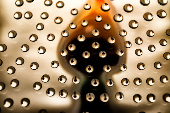 Abstract image of water droplets on a glass with a reflected silhouette of an object resembling a burning candle.