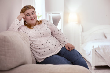 Future plans. Peaceful red-head woman sitting on the sofa while thinking about future
