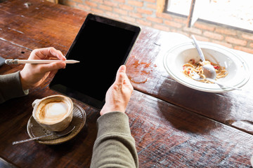 Fototapeta na wymiar Man hand use tablet blank screen on wood table with hot latte