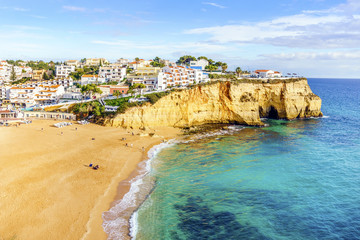 Sandy beach between cliffs in front of white architecture of Carvoeiro, Algarve, Portugal