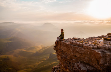 Man sitting on the cliff and enjoying sunset
