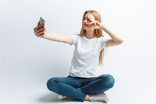 The girl in the Studio doing a selfie, white background, isolated