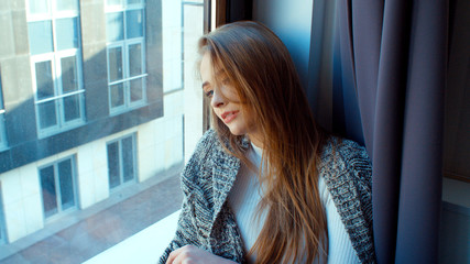 Young woman sitting by a window.