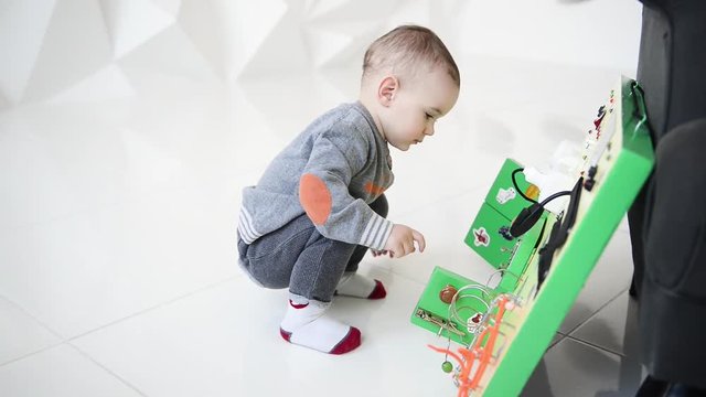 Little baby boy intently playing with busy board