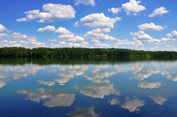 Obraz na płótnie Canvas Beautiful european landscape view, forest and summer cloudy blue sky reflected in a lake like in mirror