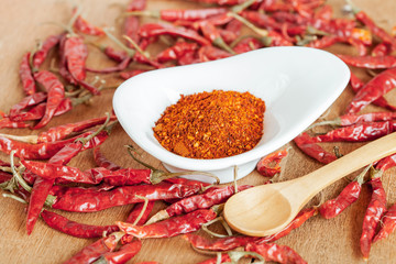 Cayenne pepper in white dish and dried chilli on wood table.