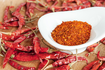 Cayenne pepper in white dish and dried chilli on wood table.