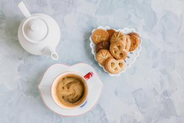 Morning coffee with milk in the original white Cup with a blue button on the background of the cookies.